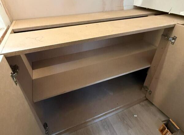 Built-in cabinet interior with fitted shelf and hinged doors during installation in Woodford Green.
