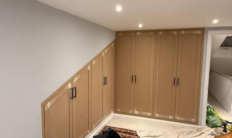 Completed fitted loft wardrobes with angled under-eaves cupboards and black handles.