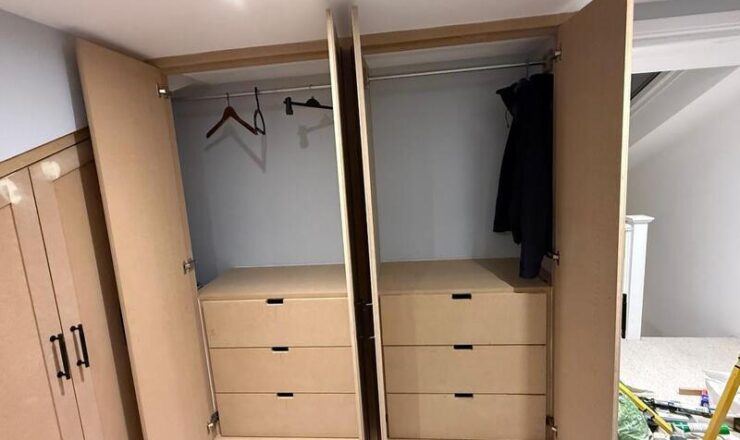 Open wardrobe showing hanging rails and integrated drawer units inside loft fitted storage.