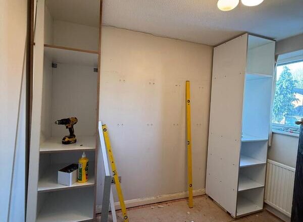 Fitted wardrobe carcasses installed in a Chingford bedroom with side shelving units.