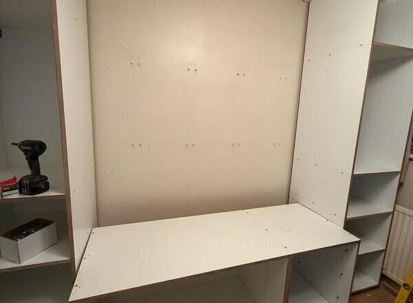 Built-in wardrobe base unit fitted between side towers, ready for finishing.