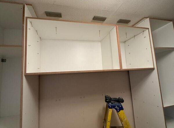 Overhead bridge cupboards installed above fitted wardrobes to maximise storage.