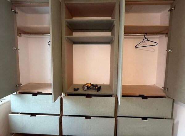 Open wardrobe showing drawer storage, shelving, and hanging rails during installation.