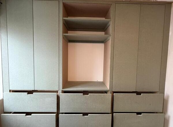 Built-in wardrobe front with tall doors and handleless drawer fronts ready for finishing.