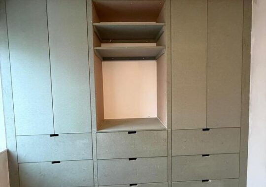Completed fitted wardrobe in Dalston with central open bay and drawer storage.