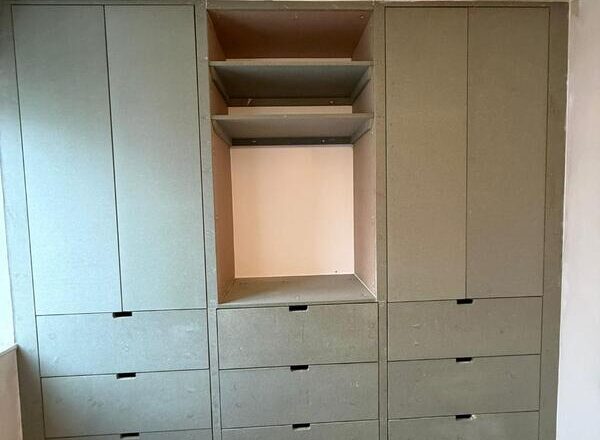 Completed fitted wardrobe in Dalston with central open bay and drawer storage.