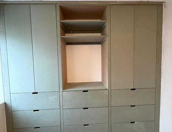 Completed fitted wardrobe in Dalston with central open bay and drawer storage.