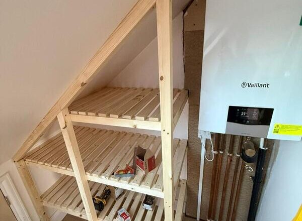 Slatted internal shelves installed inside loft boiler cabinet for under-eaves storage.