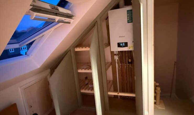 Open loft cabinet showing internal shelves and boiler access section with pipework.