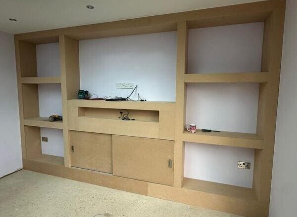 MDF media wall with fitted lower cupboards, shelving niches, and cable management space.