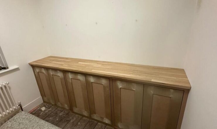 Fitted shaker-style base cupboards with timber worktop installed against wall.