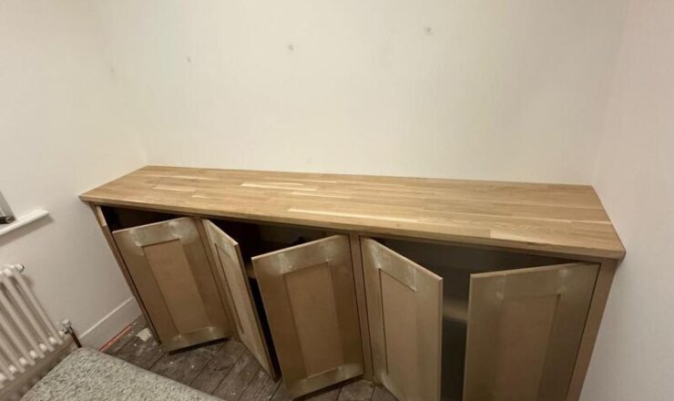 Part-open shaker doors on fitted cabinet unit during installation and alignment.