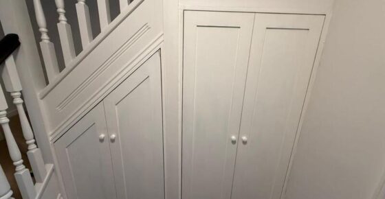 Completed under-stairs cupboards with white shaker doors and knobs, finished to match staircase.