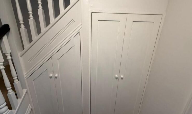 Completed under-stairs cupboards with white shaker doors and knobs, finished to match staircase.