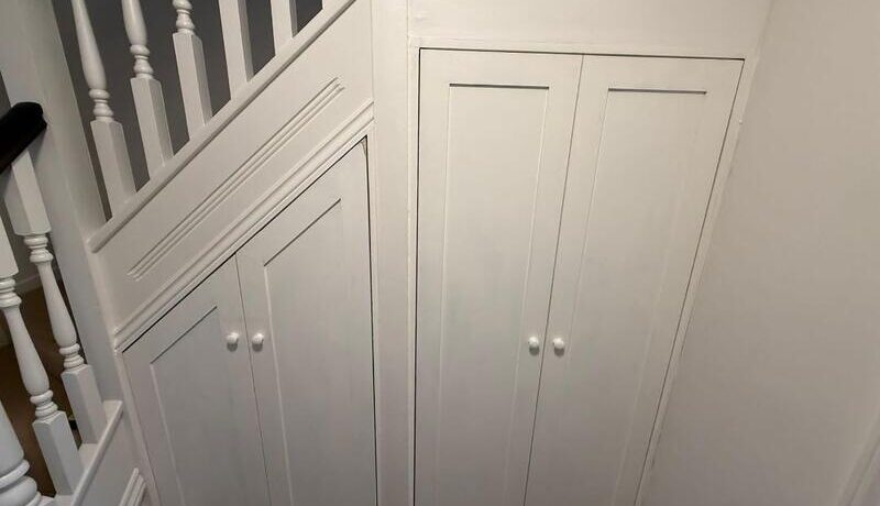 Completed under-stairs cupboards with white shaker doors and knobs, finished to match staircase.