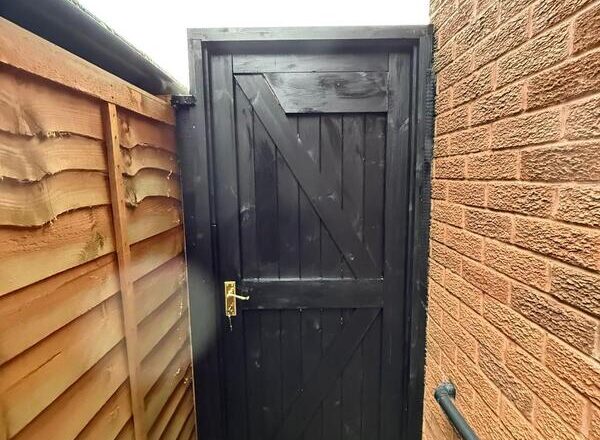 Side gate painted black with exterior finish, showing ledged and braced design.