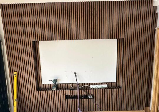 Close-up of vertical slatted media wall finish around recessed TV opening.