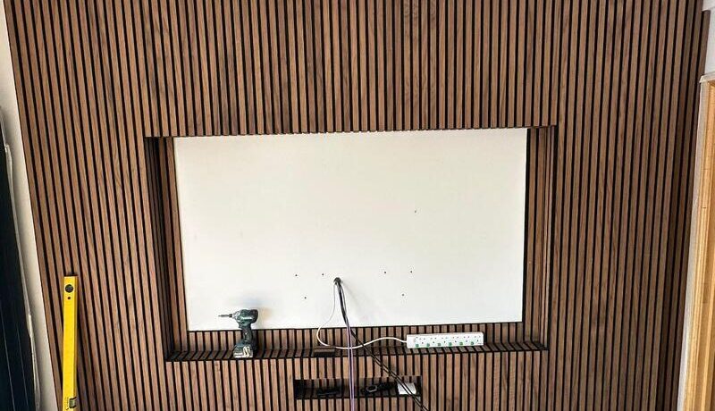 Close-up of vertical slatted media wall finish around recessed TV opening.