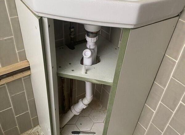 Under-sink cabinet carcass fitted with plumbing cut-outs for waste pipe and trap.