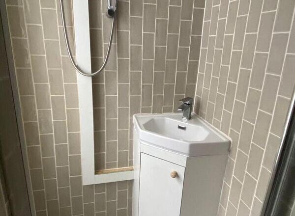 Compact corner sink vanity unit installed in Leytonstone shower room to conceal pipework.