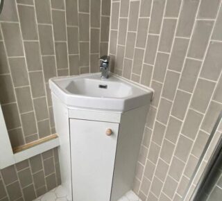 Completed under-sink cabinet providing hidden storage and a tidy finish around corner basin.