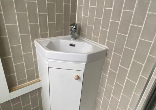 Completed under-sink cabinet providing hidden storage and a tidy finish around corner basin.