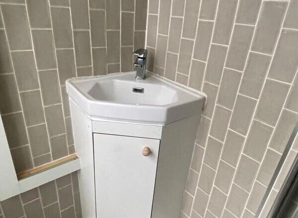 Completed under-sink cabinet providing hidden storage and a tidy finish around corner basin.