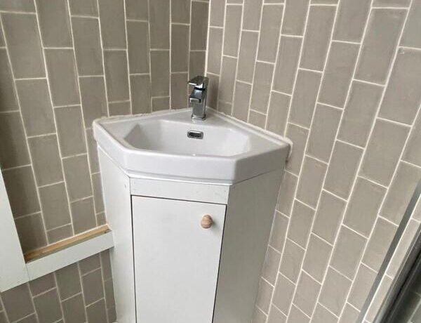 Completed under-sink cabinet providing hidden storage and a tidy finish around corner basin.