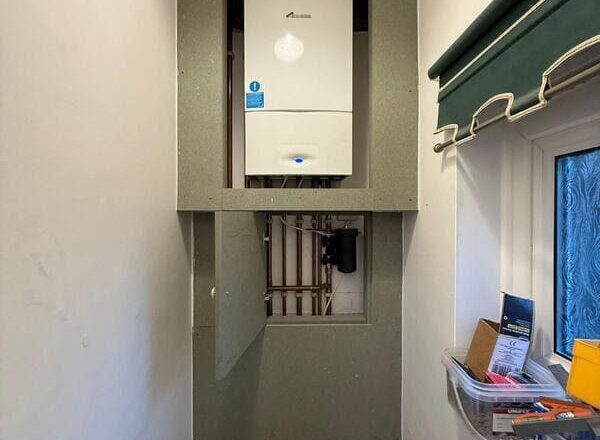 Open service hatch showing accessible pipework inside the boxed-in boiler cabinet.
