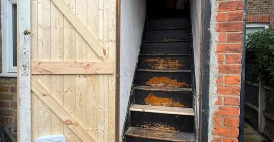 Open rear timber door showing access to interior staircase after refurbishment work.