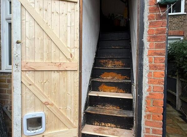 Open rear timber door showing access to interior staircase after refurbishment work.