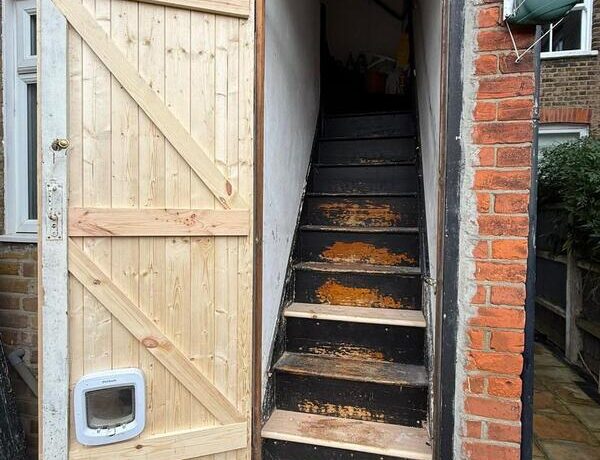 Open rear timber door showing access to interior staircase after refurbishment work.